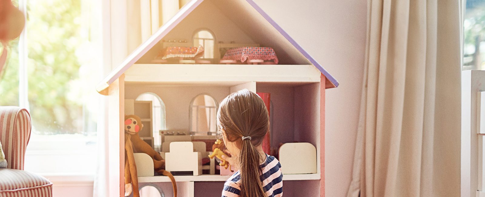 Stock child playing with dollhouse